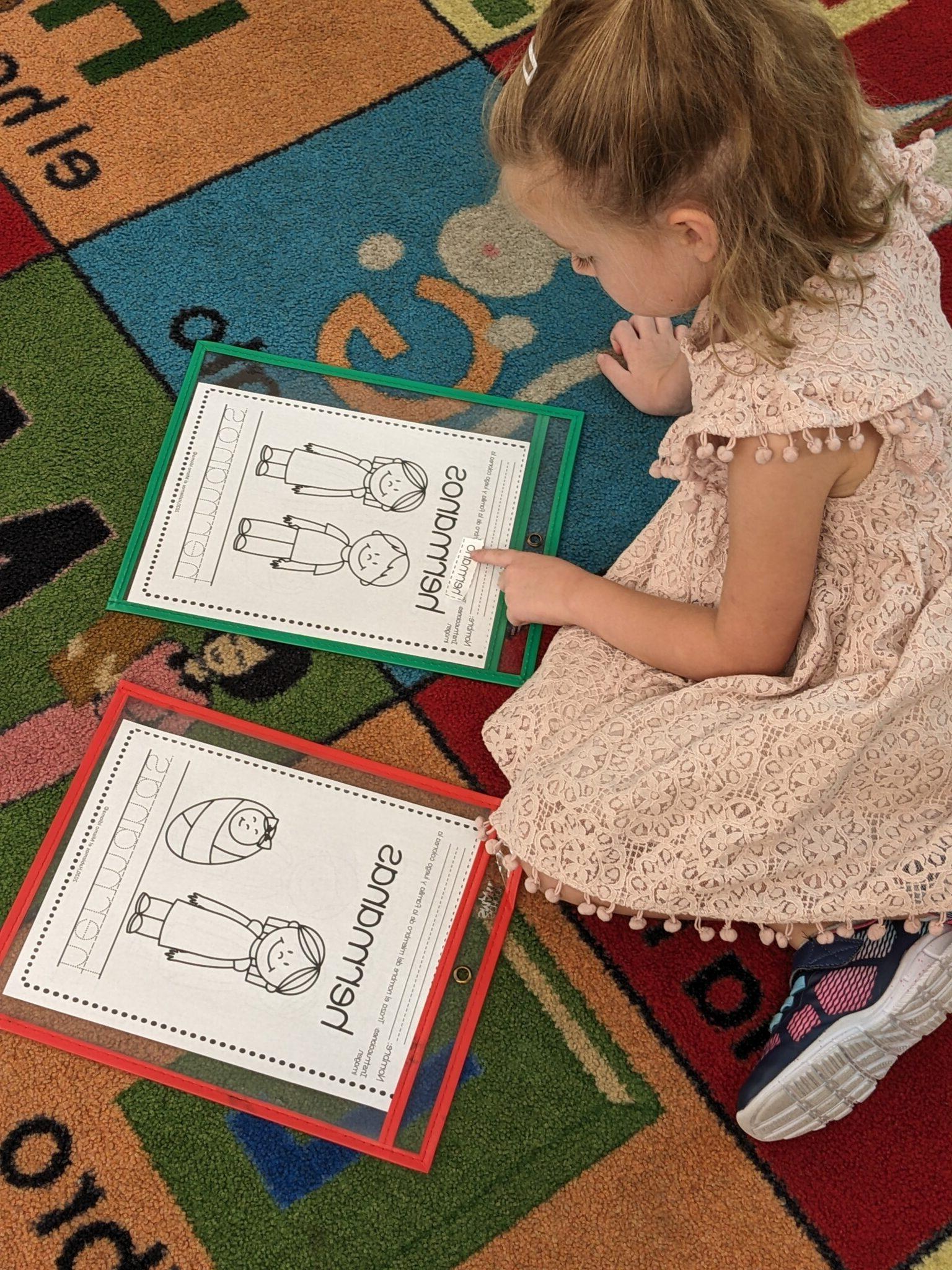 学生学习西班牙家庭词汇. 她坐在地板上看着照片和家庭用语.